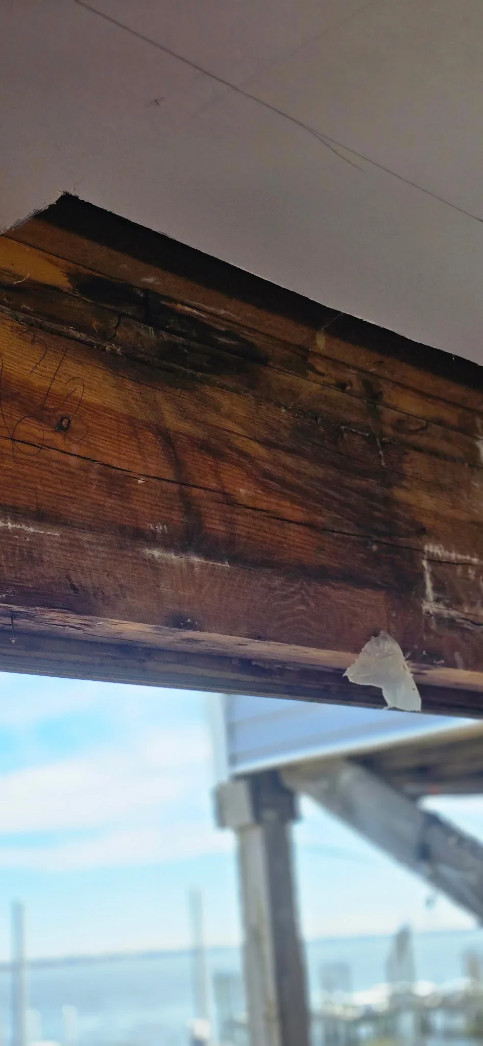 Charred wooden soffit and fascia with heat damage, showing exposed framing and deteriorated wood