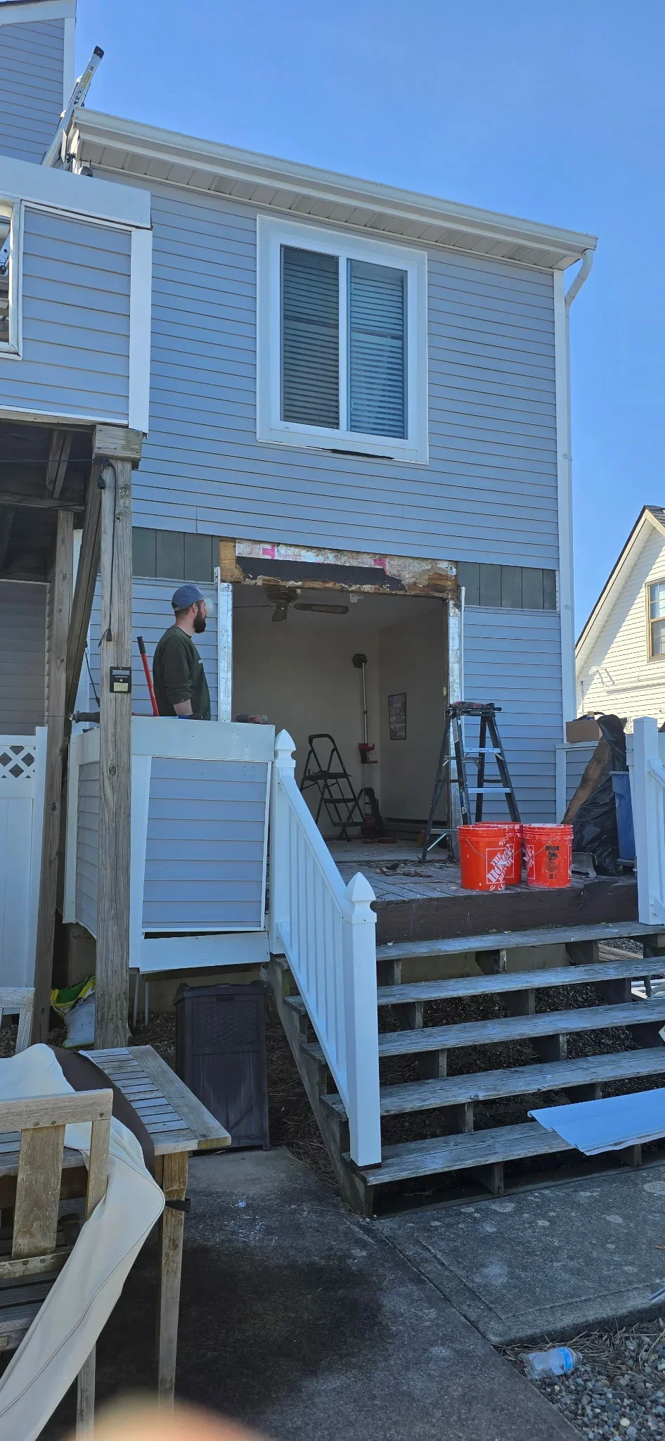 New exterior door installation with blue horizontal siding and white trim on residential home