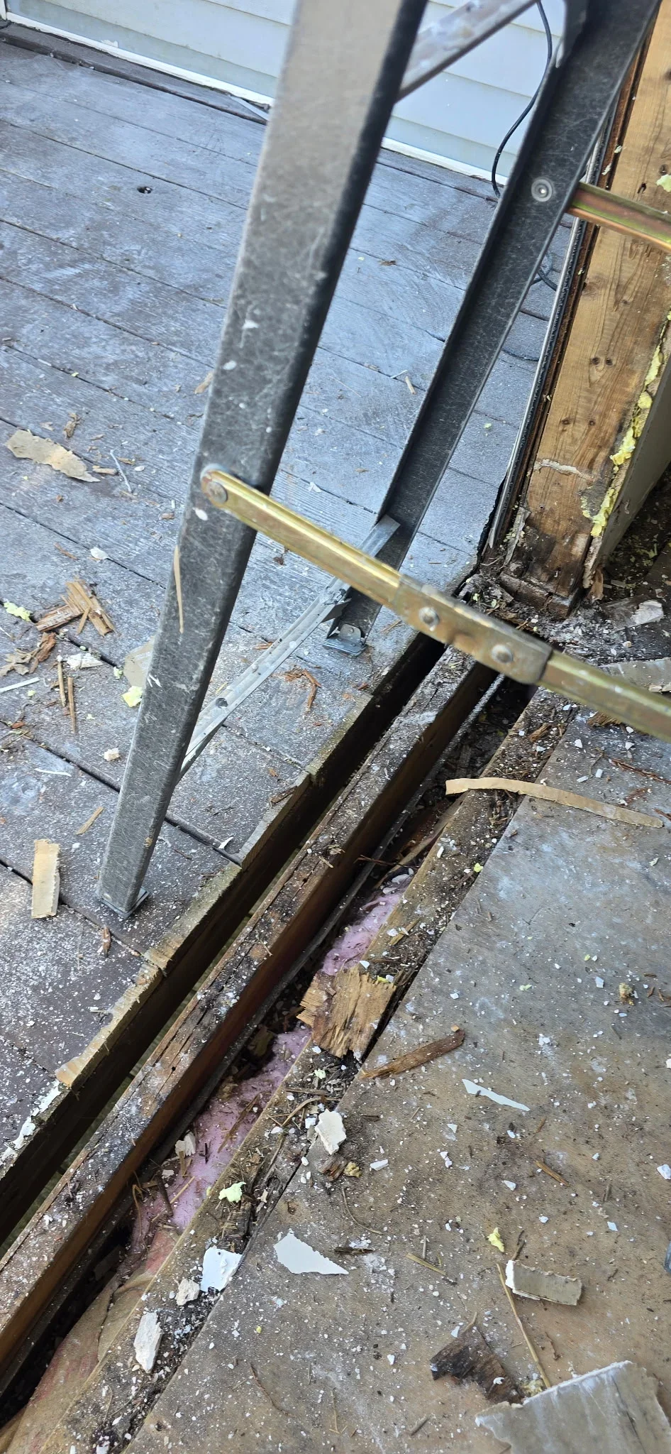Wooden subfloor framing and brass threshold hardware installation at doorway transition