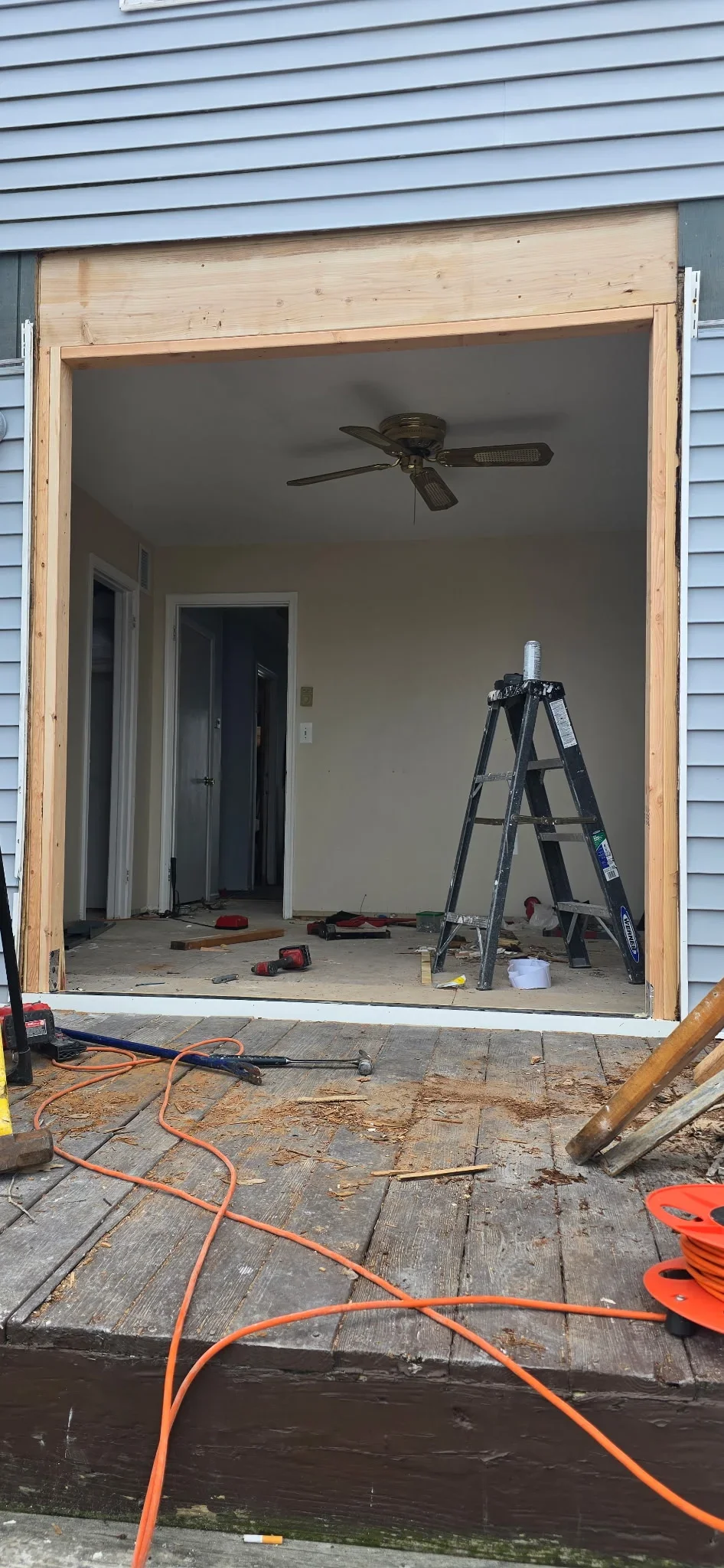 Drywall-lined room addition with framed doorways, ceiling fan, and construction in progress