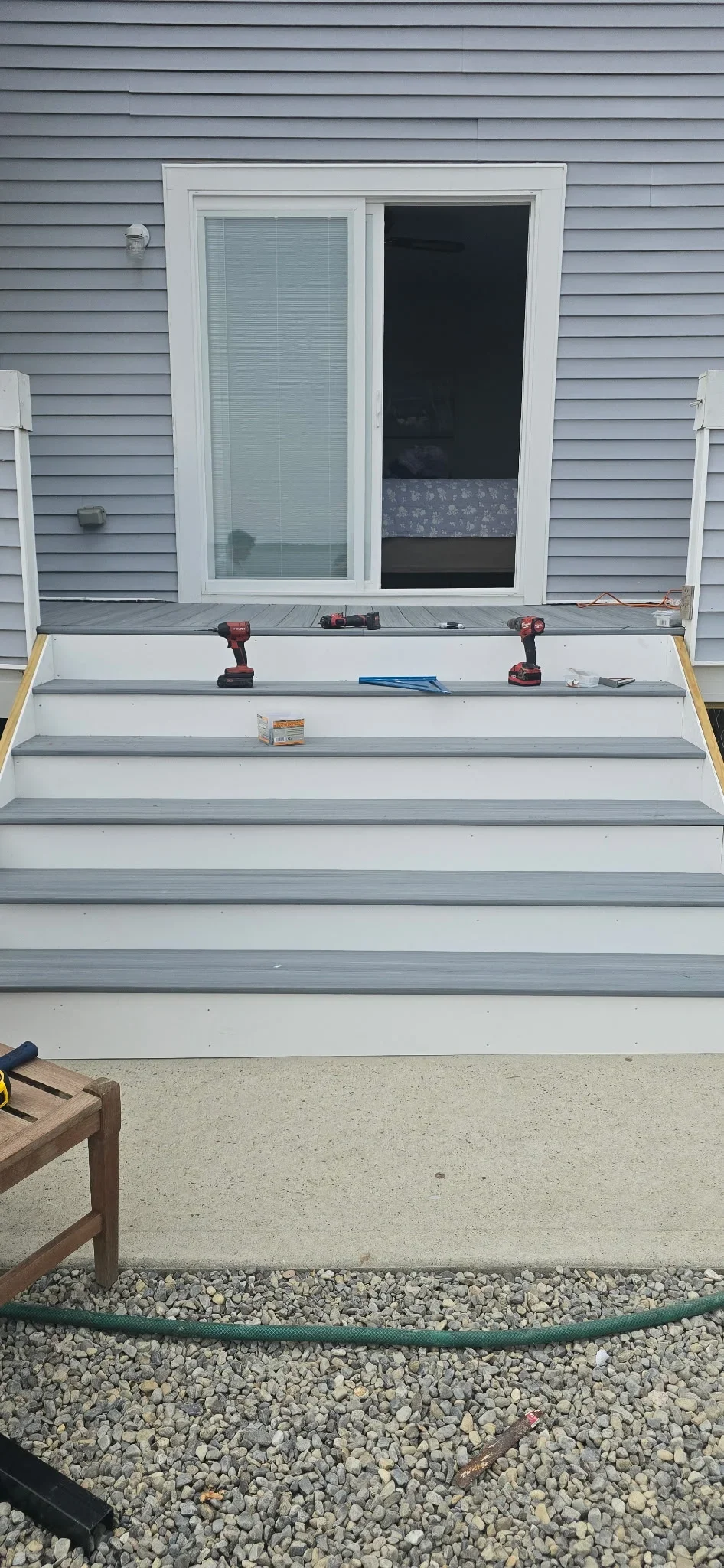 Multi-level composite deck with gray boards, white door frame, and gravel base