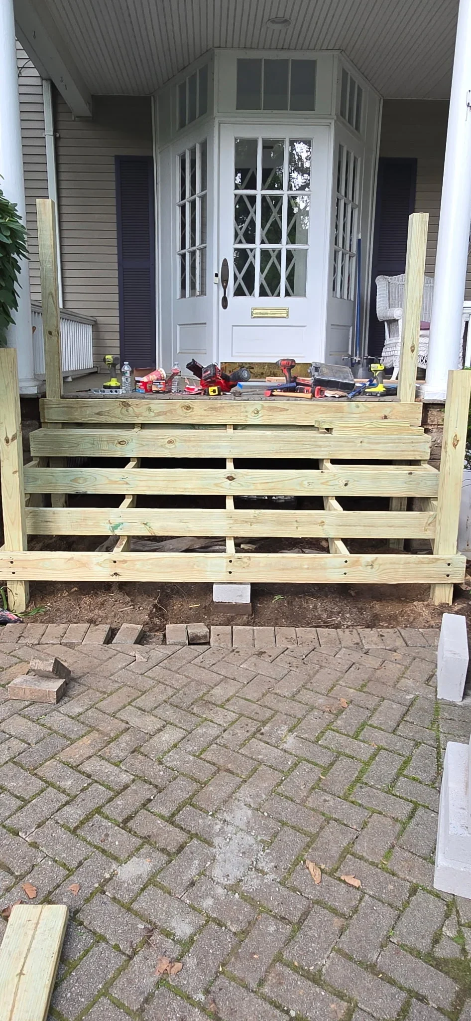 Pressure-treated deck framing with joists and beams, concrete pier supports visible