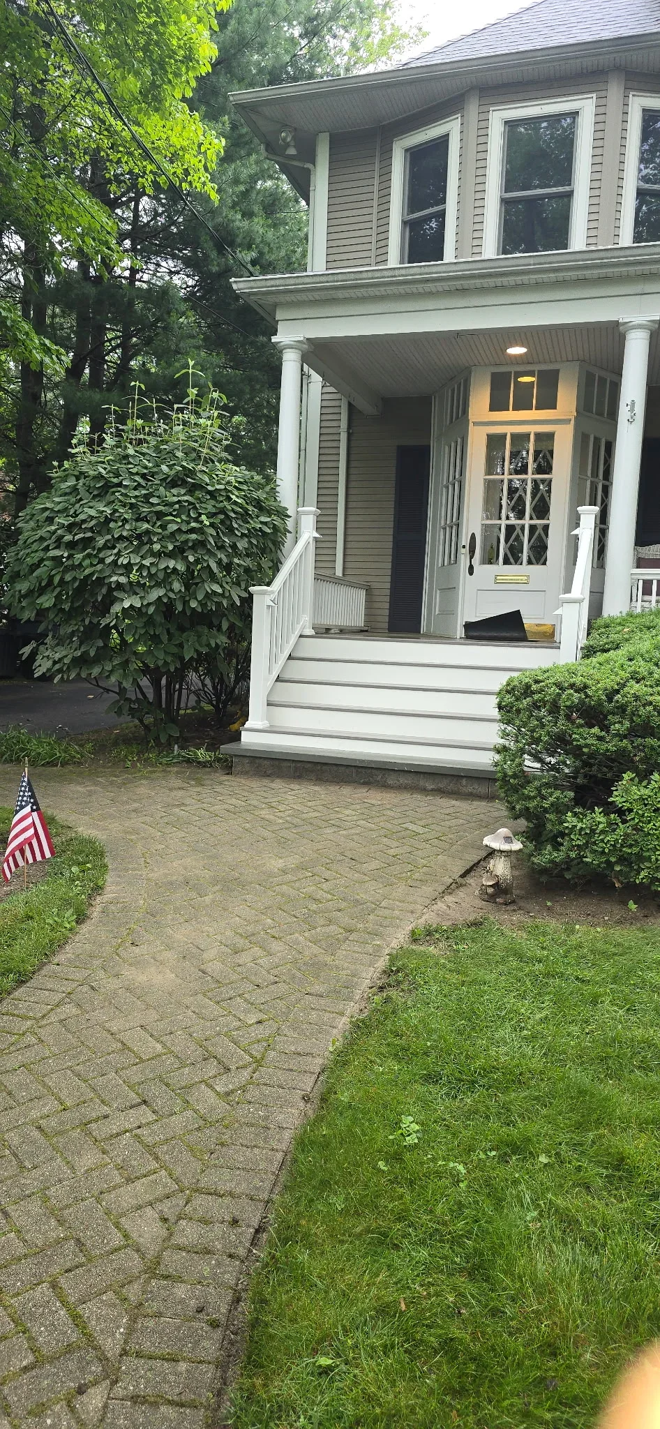 Paver walkway and white front porch steps with columns on residential home