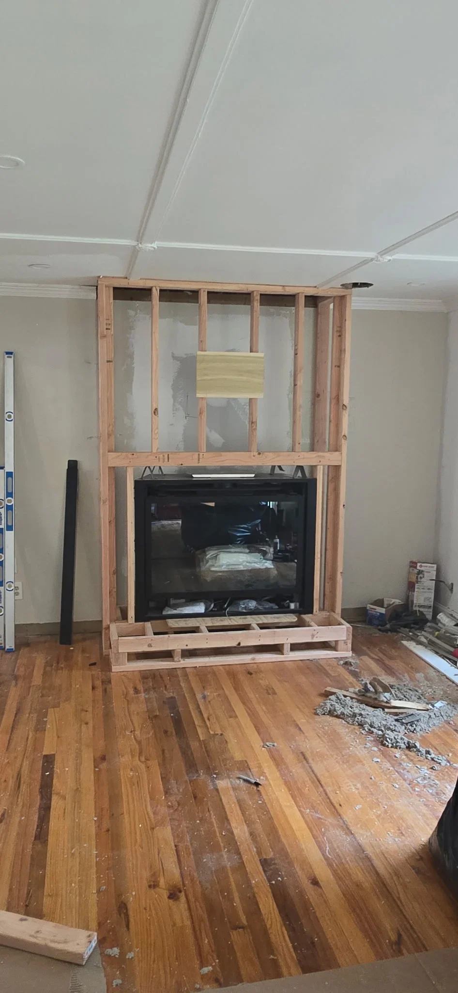 Wood-framed fireplace surround with black insert, glass panels, and dimensional lumber construction