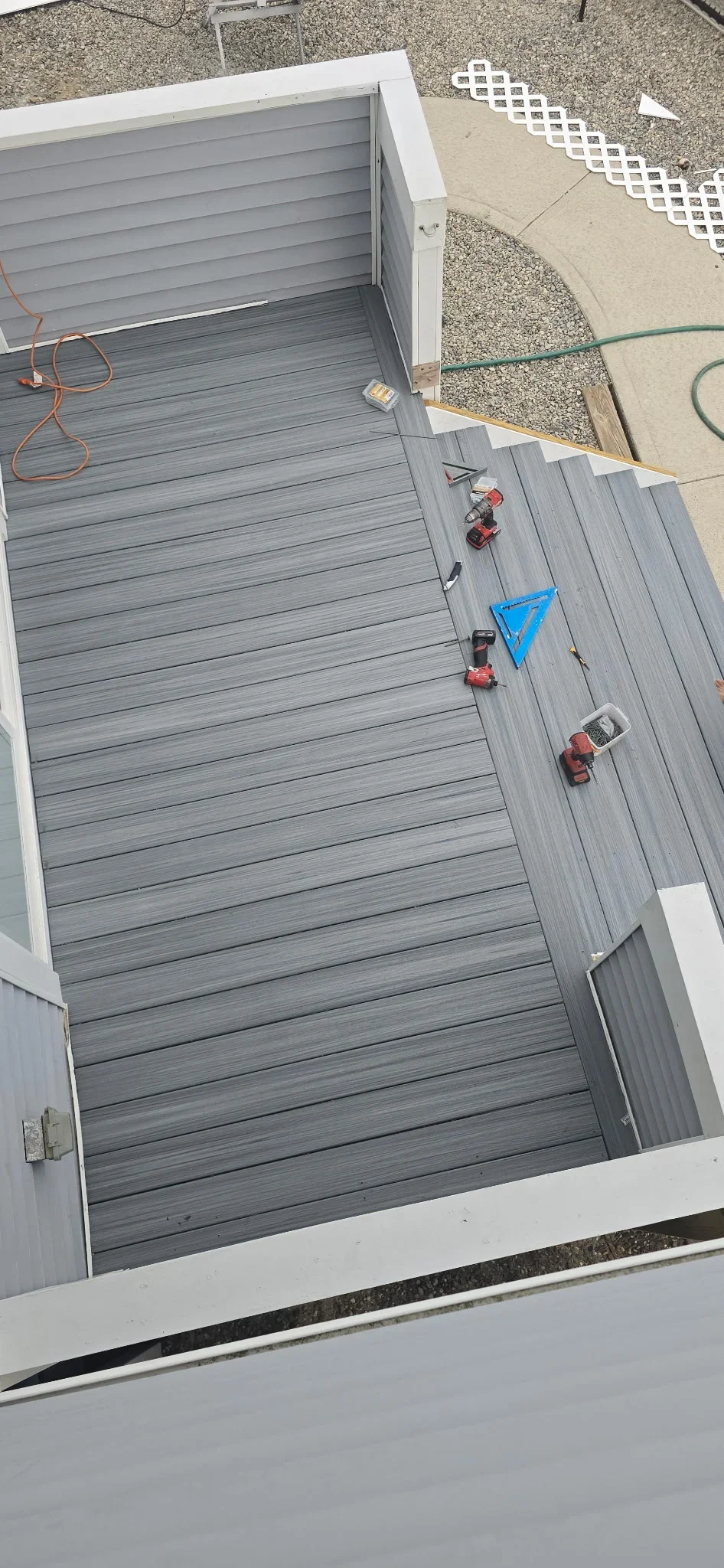 Gray composite deck boards with white trim and installation equipment visible from above